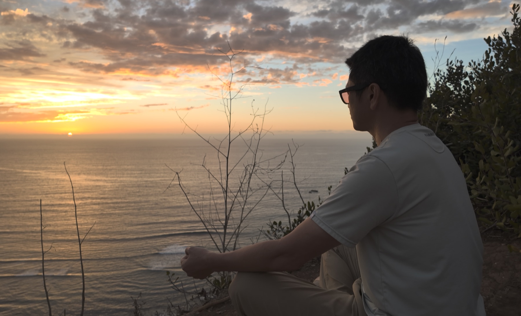 海に沈む夕日を眺めながら静かに座る小崎壮平