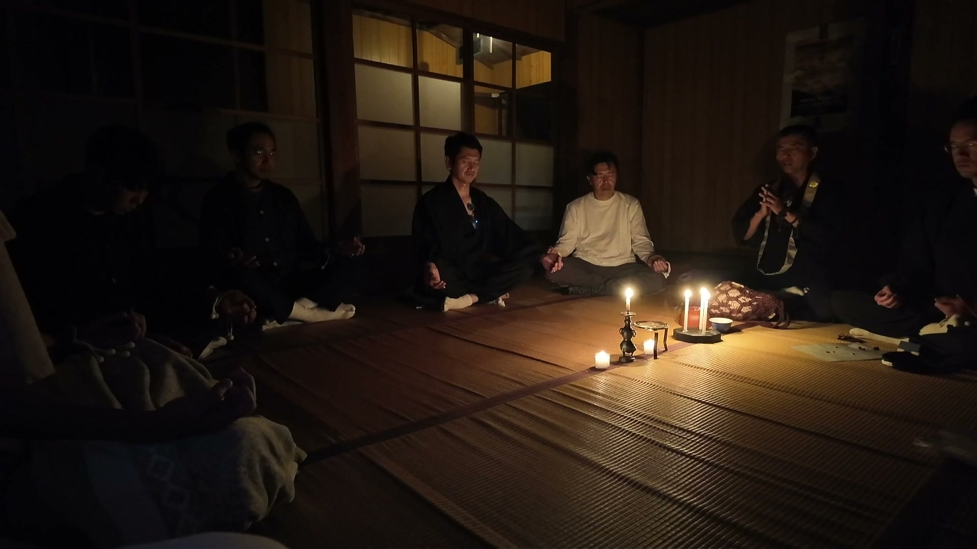 ろうそくの灯りを囲んで瞑想する参加者